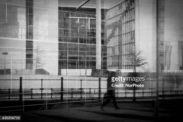 Man walking past a government building is seen reflected in a glass wall on 13 February, 2017.