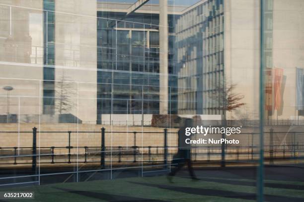 Man walking past a government building is seen reflected in a glass wall on 13 February, 2017.