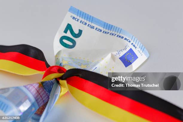 Berlin, Germany In this Photo Illustration a 20 Euro bill is wrapped round with a ribbon in the national colors of Germany on February 14, 2017 in...