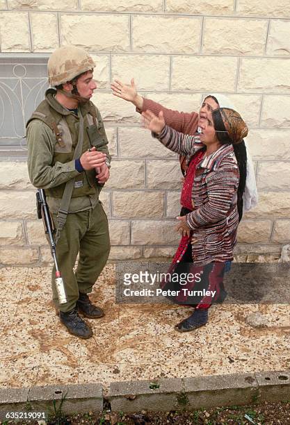 Palestinian women harass an Israeli soldier guarding the streets during the Intifada, an uprising of Palestinians against Israel occupation.