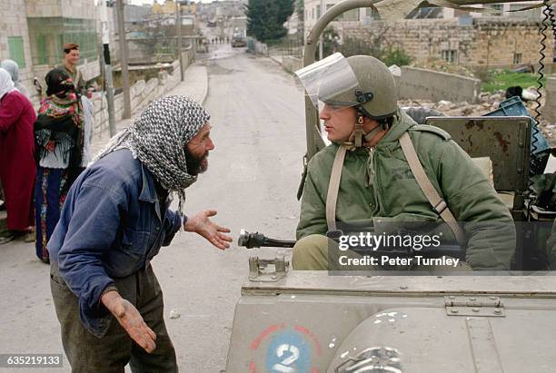 Palestinian man pleads with an Israeli soldier for the release of a boy being held in Am'Ari camp.