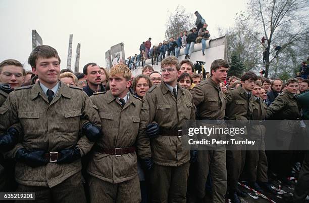 East German soldiers link arms during the dismantling of the Berlin Wall.