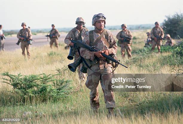 Marines move through the grass after landing by helicopter at the Baidoa airport as part of "Operation Restore Hope" in December of 1992. In the...