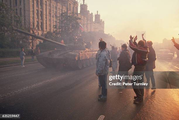 Crowds cheer as Russian soldiers pass by them in tanks following their defection to the side of Boris Yeltsin during the coup attempt by Soviet...