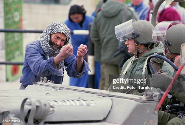 An emotional Palestinian man speaks to two Israeli soldiers during the Intifada.