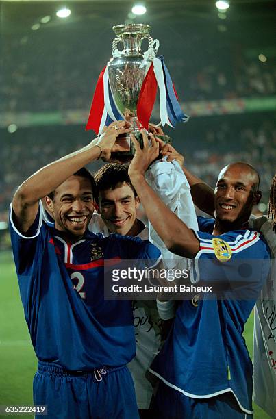 French players Thierry Henry, Robert Pires and Nicolas Anelka celebrate victory, holding their trophy high, following the 2000 UEFA European...