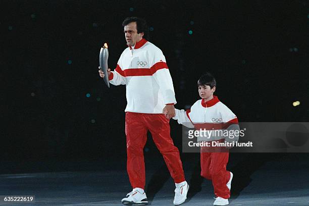 Former French soccer champion Michel Platini and Francois-Cyrille Grange walk with the Olympic torch during the 1992 Winter Olympic Games opening...