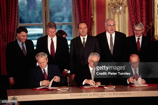 Serbian President Slobodan Milosevic, Croat President Franjo Tudjman, and Bosnian President Alija Izetbegovic sign multiple copies of the Dayton...