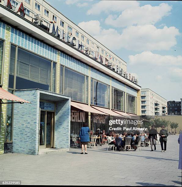 People sit outdoors at cafe tables on Karl Marx Avenue in East Berlin, Germany, 1967.