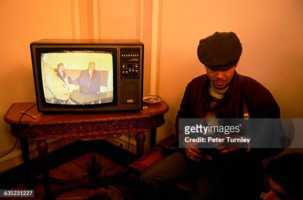 An armed rebel sits beside Nicolae Ceausescu's own office television set as it broadcasts a tape of the trial of Ceausescu and his wife Elena. The...