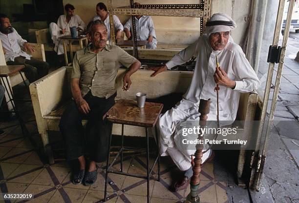 Two men sit in a tea shop on El Rachid Street. The one on the right is smoking a hookah.