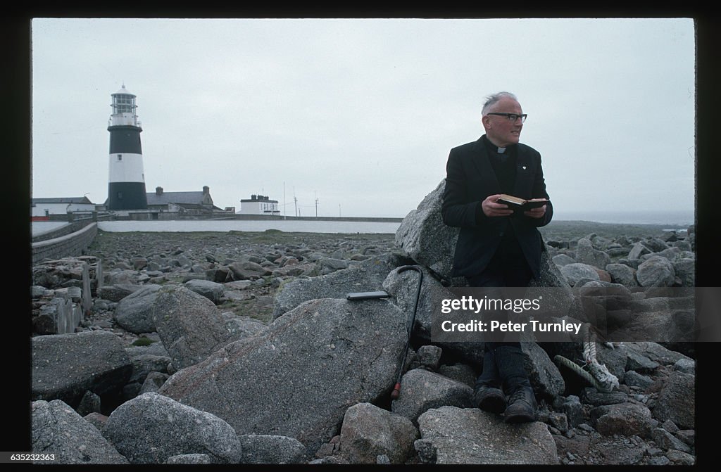 Priest Reading Bible by Lighthouse