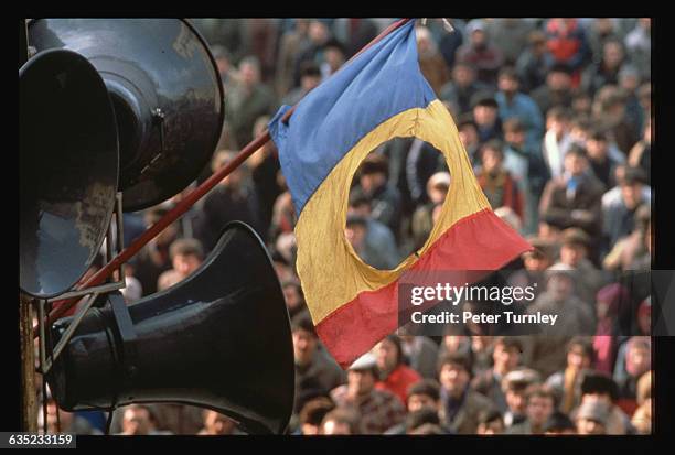 Romanian flag with the Communist symbol torn from its center flies over Palace Square in Bucharest during the revolution of 1989.