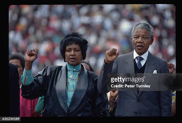 Nelson and Winnie Mandela raise their fists and sing with the crowd at a Soweto rally celebrating Nelson's release from prison.