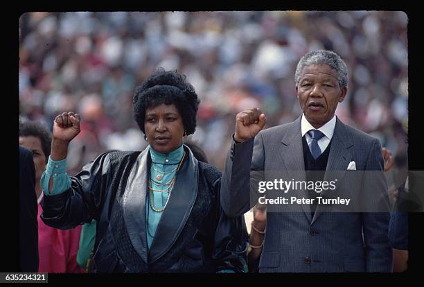 Nelson and Winnie Mandela raise their fists and sing with the crowd at a Soweto rally celebrating Nelson's release from prison.