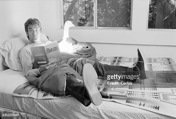 Singer Huey Lewis poses at home, holding a glowing toy duck and a copy of The Nuclear Threat to Marin County.