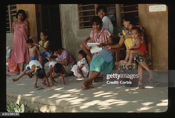 Mothers give their boys haircuts at an evacuation camp. The had to leave Volcano Island before the Taal Volcano erupted. | Location: Venancio...