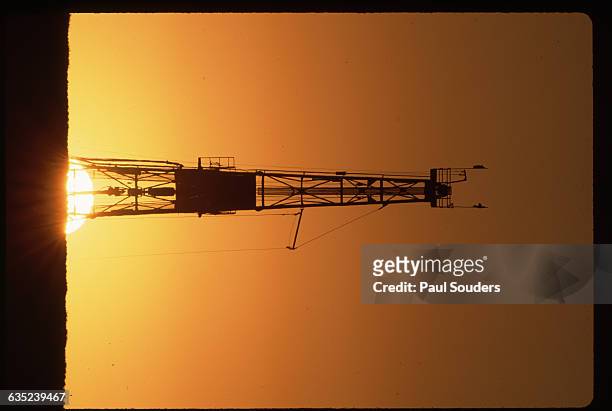 The sun sets over an oil drilling platform in the middle of a wheatfield near Edmonton, Alberta, Canada. A hole 1300 meters deep has been drilled...