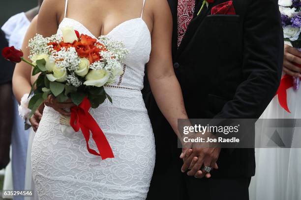 Couple stands together as they participate in a group Valentine's day wedding ceremony at the National Croquet Center on February 14, 2017 in West...