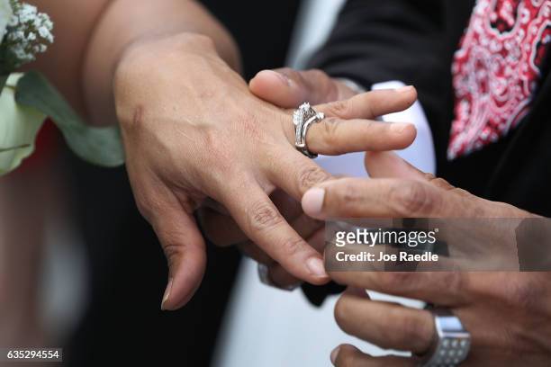 Couple exchanges rings as they participate in a group Valentine's day wedding ceremony at the National Croquet Center on February 14, 2017 in West...