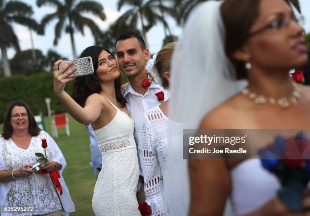 Couple take a selfie as they participate in a group Valentine's day wedding ceremony at the National Croquet Center on February 14, 2017 in West Palm...