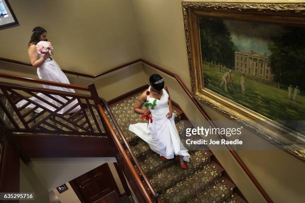 Brides walk down the stairs as they participate in a group Valentine's day wedding ceremony at the National Croquet Center on February 14, 2017 in...