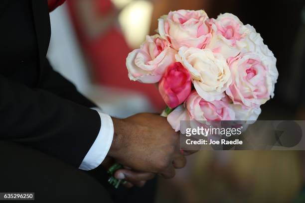 Bouquet of flowers is held by a groom before a group Valentine's day wedding ceremony at the National Croquet Center on February 14, 2017 in West...