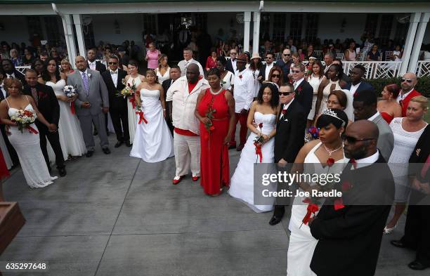 Couples stand together as they participate in a group Valentine's day wedding ceremony at the National Croquet Center on February 14, 2017 in West...