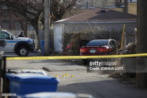 Chicago Police crime scene tape and evidence markers are seen in a alley near a vehicle riddled with bullet holes as police investigate a triple...