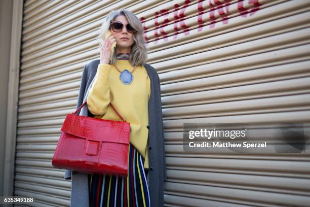 Samantha Angelo is seen attending ICB during New York Fashion Week wearing a grey wool coat, yellow sweater, striped skirt and red bag on February...