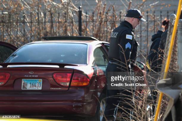 Police look over a bullet-riddled car after a gunman opened fire killing a two-year-old child, a man in his twenties and wounding a pregnant woman in...