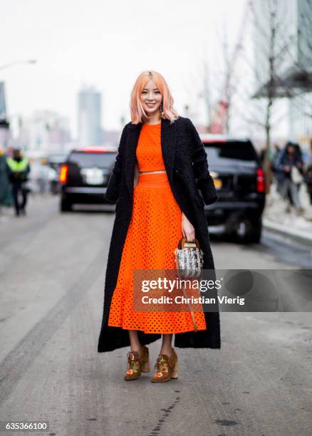 Irene Kim wearing an orange dress, black coat outside Tory Burch on February 14, 2017 in New York City.