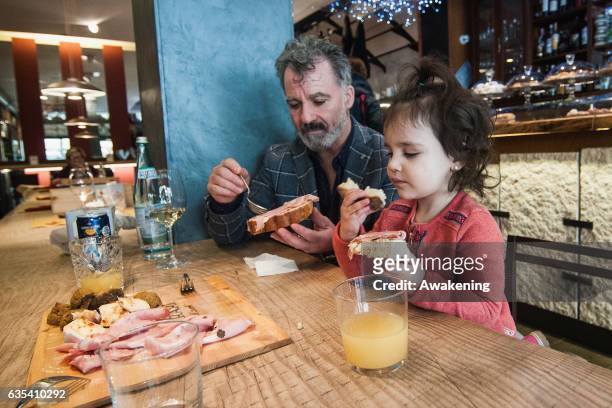 Child eats with her parents for lunch at a table in the Antonio Ferrari restaurant on February 15, 2017 in Padova, Italy. The restaurant offers a 5%...