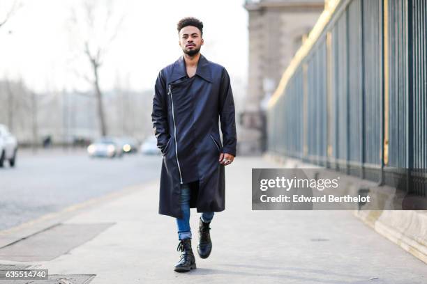 Theo Kimbaloula, fashion blogger, wears a Zwitter Paris black leather long coat, Asos blue denim jeans, and Asos boots, on February 12, 2017 in...