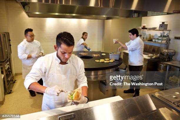 Jorge Ortiz fills an arepa while behind him from left to right: Yic Tam, Albani Caolo and sous chef Nacho Useche work at the arepas grill at Alma...
