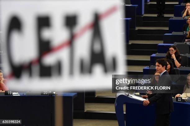 Person holds up a sign against the EU-Canada Comprehensive Economic and Trade Agreement as Canadian Prime Minister Justin Trudeau speaks during a...