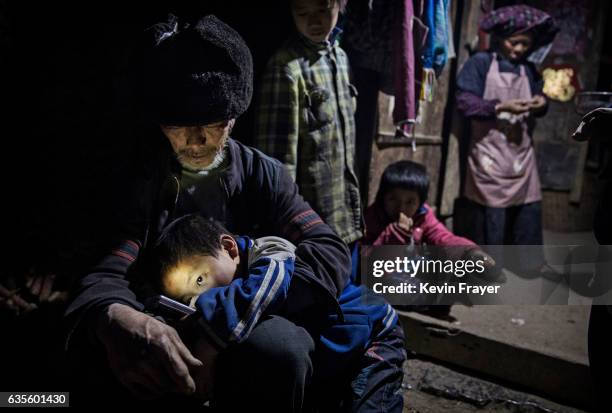 Grandfather Luo Yingtao holds his grandson 'left behind' child Luo Lie in his lap as they sit at the family house on December 15, 2016 in Anshun,...