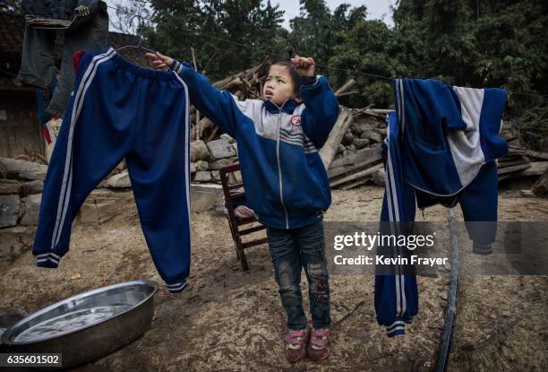 Left behind' child Luo Hongniu hangs laundry after washing clothes with her siblings on December 18, 2016 in Anshun, China. Like millions of Chinese...