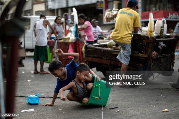 Children play with a plastic container with wheels along a street in Divisoria Market in Manila on February 16, 2017. / AFP / Noel CELIS