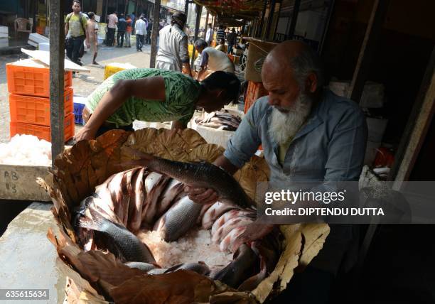 Indian fish traders arrange a basket of fish for potential customers at a local fish market in Siliguri on February 16, 2017. Fishing plays an...