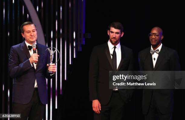 Swimmer Michael Phelps of the USA and Laureus Academy member Edwin Moses look on as Chairman and owner of the Chicago Cubs Tom Ricketts accepts the...