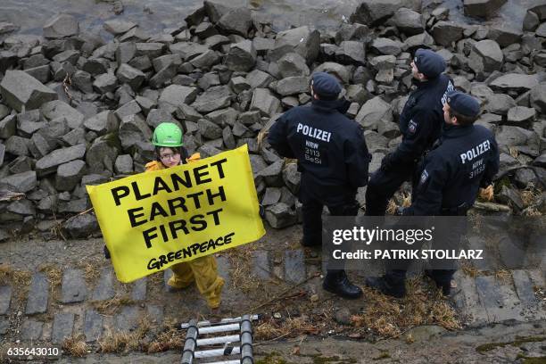 Police look on as members of Greenpeace raise a banner which reads "Planet Earth First" on their ship, the Beluga, on the banks of the river Rhein...