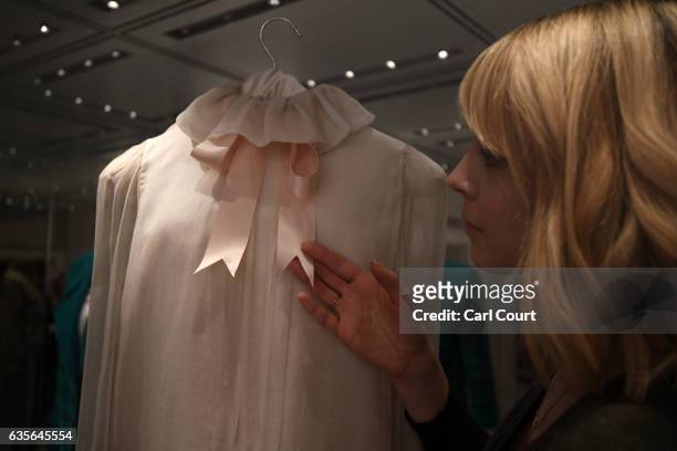 Member of staff poses with a 1981 Emanuel pale pink chiffon blouse with a satin neck-ribbon worn during Diana's first official portrait in 1981...