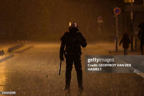 An anti riot policeman stands guard as people gather in Bobigny, northern Paris, on February 16, 2017 during a demonstration to demand justice for...