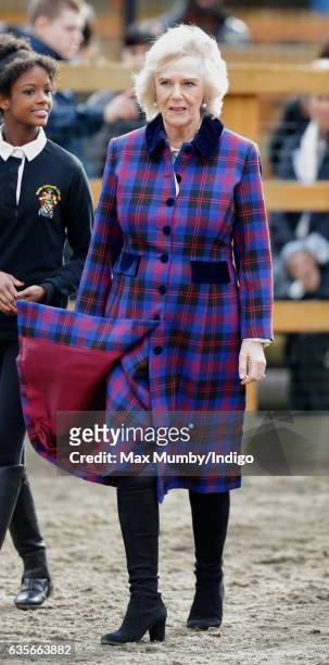 Camilla, Duchess of Cornwall's hair and coat are blown in the wind as she visits the Ebony Horse Club riding centre to celebrate the club's 21st...