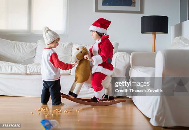 boy in red santa claus costume sits on a toy horse - baby toy stock pictures, royalty-free photos & images