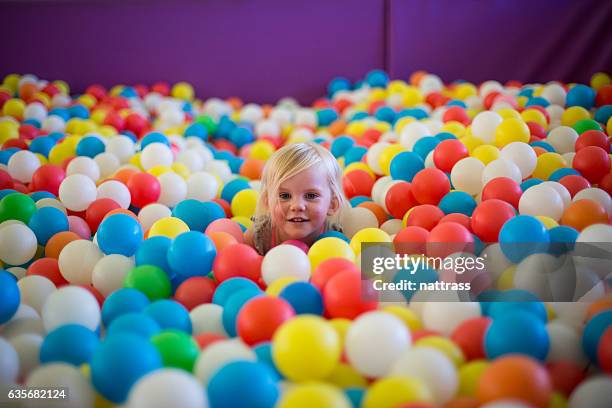 kleine blonde mädchen spielt in einem bunten ballpool - playground stock-fotos und bilder