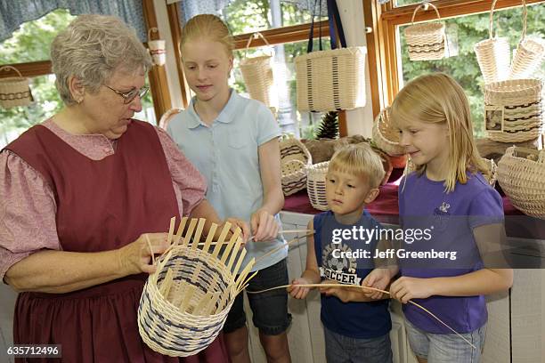 Woman demonstrating how to weave a basket in a basketmaker shop.