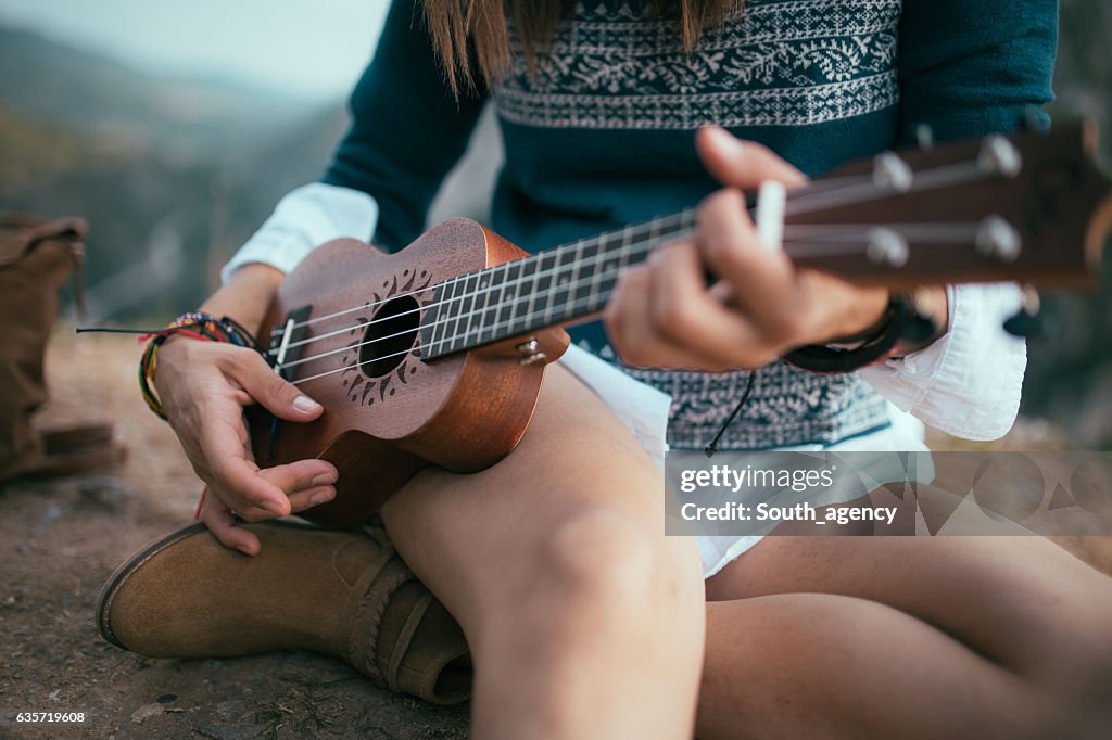 Hippie spielen wie man ukulele spielt auf dem Berggipfel