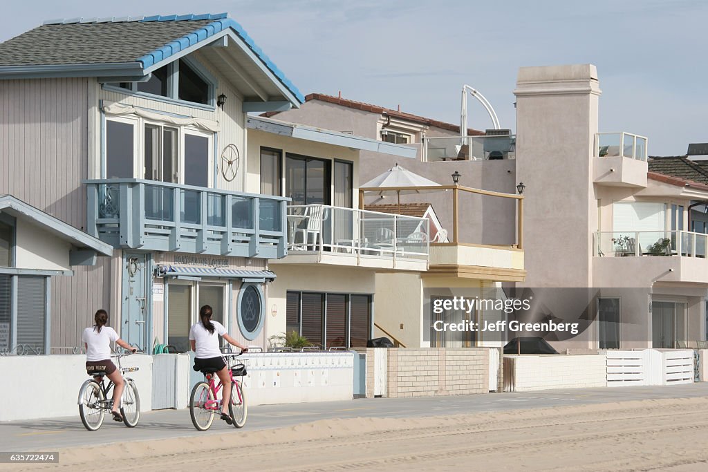 Female bicyclists in front of beachfront homes at Balboa Peninsula.